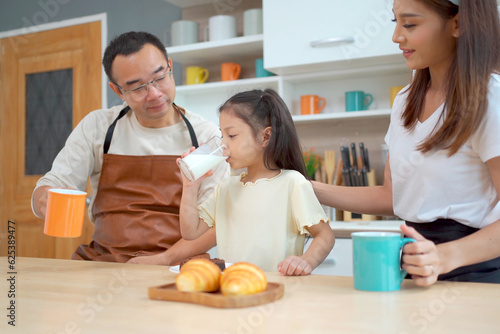 Happy Asian family with father, mother, and little girl enjoy cooking and having a breakfast together.