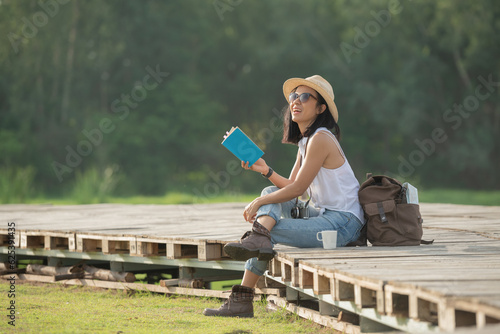 asian woman traveler with backpack relaxing outdoor with sitting on quayside relax read book during coffee break on background summer vacations and lifestyle hiking concept.