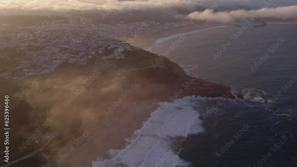 Wide shot of Nazaré town Portugal during sunrise with low clouds, aerial Wide shot of Nazaré town Portugal during sunrise with low clouds, aerial