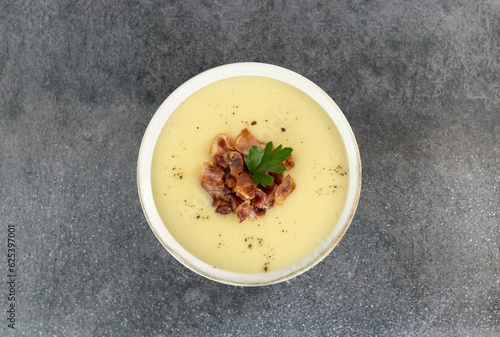 Bowl of creamy potato or cauliflower soup with bacon on a gray background. Top view. French vichyssoise soup.