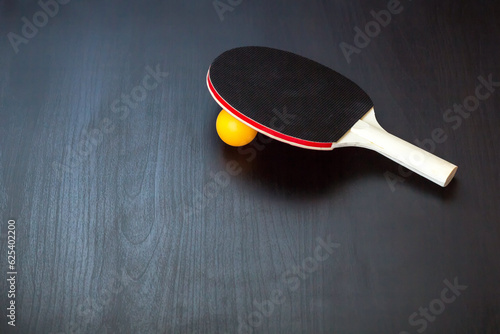 table tennis or ping pong racket and ball on a black background