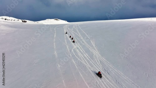 Aerial view of people riding snowmobiles on the icy ground of Myrdalsjokull glacier in Iceland photo