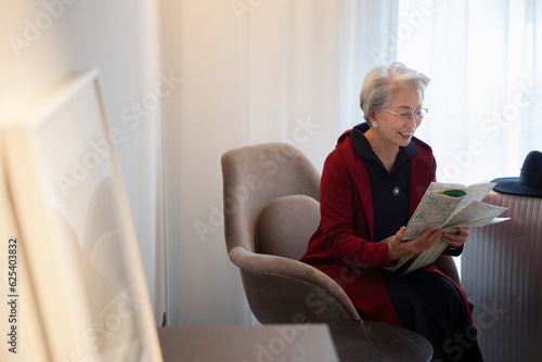 一人旅をする高齢女性が宿泊先のホテルで地図を開いている photo