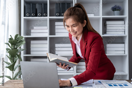 Young Asian happy professional business woman worker employee sit at office desk and working on computer and calculator, Accountant calculation taxes rates firm law account on computer