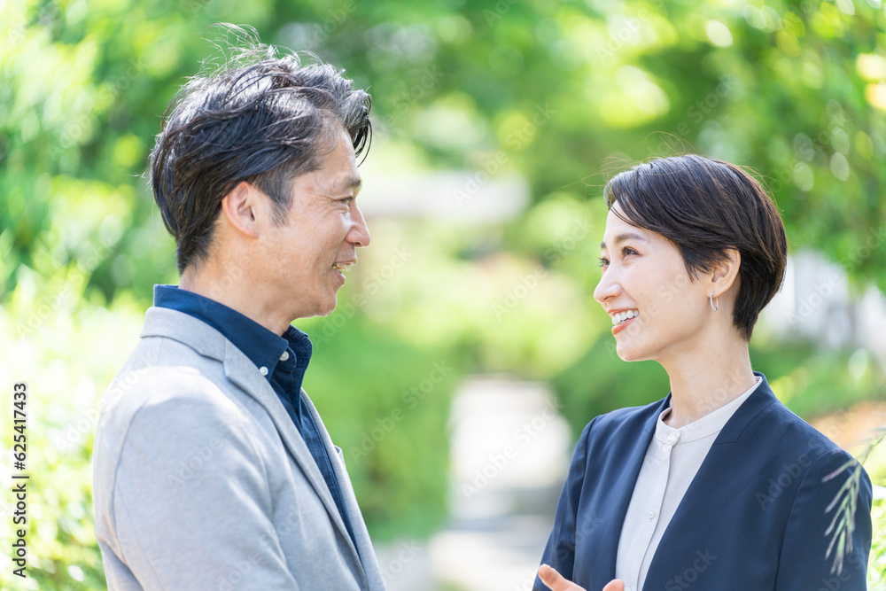 屋外の新緑の前に立つビジネスマンたち