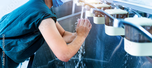 Young female doctor washing hands before operation photo