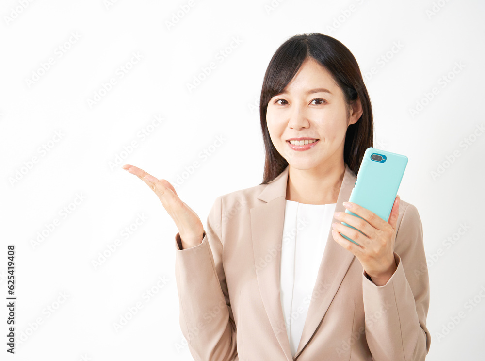 スマートフォンを持って手のひらで左側を指すミドルエイジのビジネスウーマン　白背景