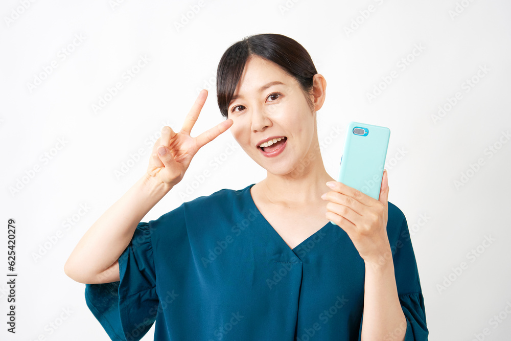 スマートフォンを持ってピースサインをする女性 白背景 スマートフォンを持ってピースサインをする女性 白背景