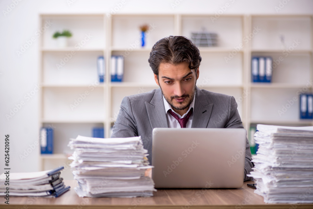 Obraz premium Young male employee and too much work in the office