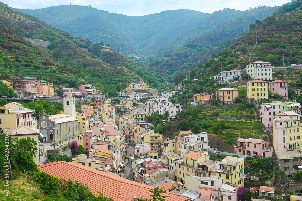 Cinque Terre, Italy - view of colorful houses, hills, vineyards of Riomaggiore, a seaside town on the Italian Riviera. Summer travel vacation background. Postcard from Europe. Italian architecture.