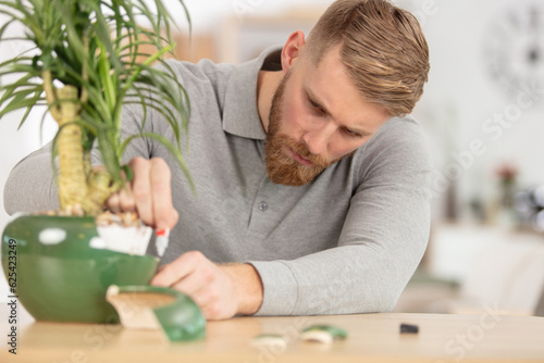man repairs broken plant pot with glue