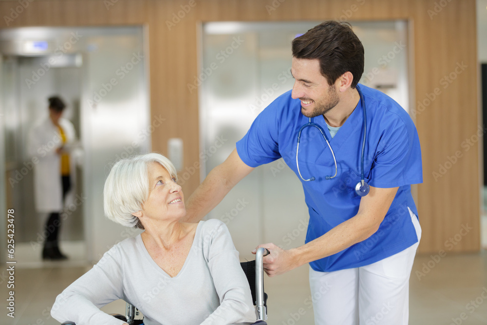 Fototapeta premium male nurse assisting elderly woman in wheelchair indoors