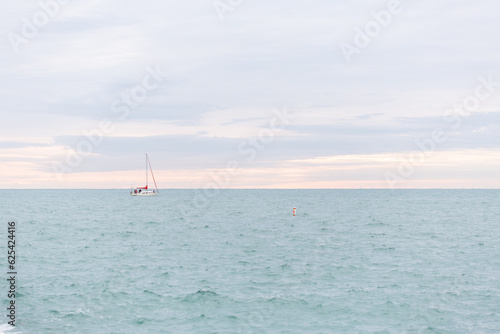 A sailboat on Lake Michigan against a pink streaked morning sky