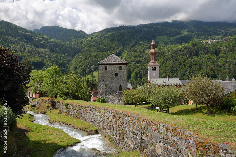 The church of Saint Francois de Sales and the Tour de Bozel (Bozel tower), located in the commune Bozel, Northern French Alps, Tarentaise, Savoie, France, with the mountain stream Le Bonrieu The church of Saint Francois de Sales and the Tour de Bozel (Bozel tower), located in the commune Bozel, Northern French Alps, Tarentaise, Savoie, France, with the mountain stream Le Bonrieu