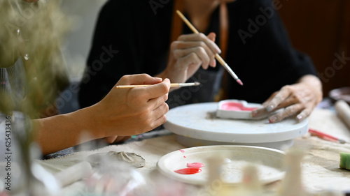 Image of young asian man enjoying creative process, creating handmade ceramics in pottery workshop