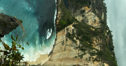 Vertical Static shot overlooking Diamond Beach on Nusa Penida Bali from the top of the cliff on a slightly overcast day with the wind blowing. Vertical shot for social media photo