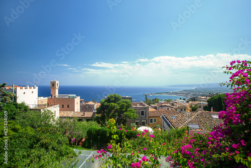 Photograph of the coast of Taormina in Sicily, houses, boats and trees.