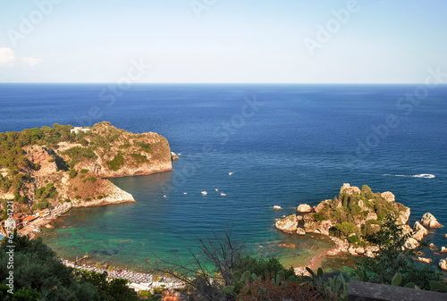 Photograph of the beautiful Isola Bella in the coast of Taormina in Sicily, houses, boats and trees.