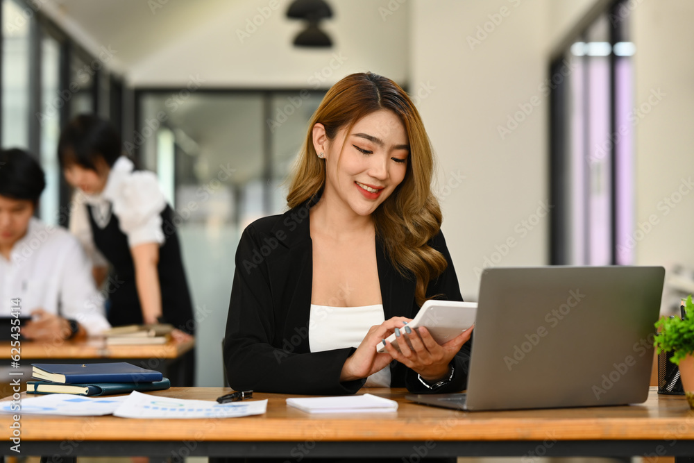 Millennial asian female manager using calculator and checking financial reports at office desk Millennial asian female manager using calculator and checking financial reports at office desk