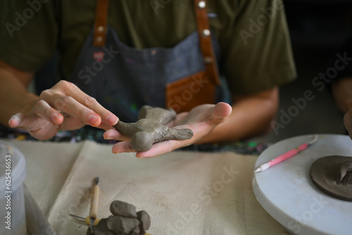 Image of young asian man enjoying creative process, creating handmade ceramics in pottery workshop