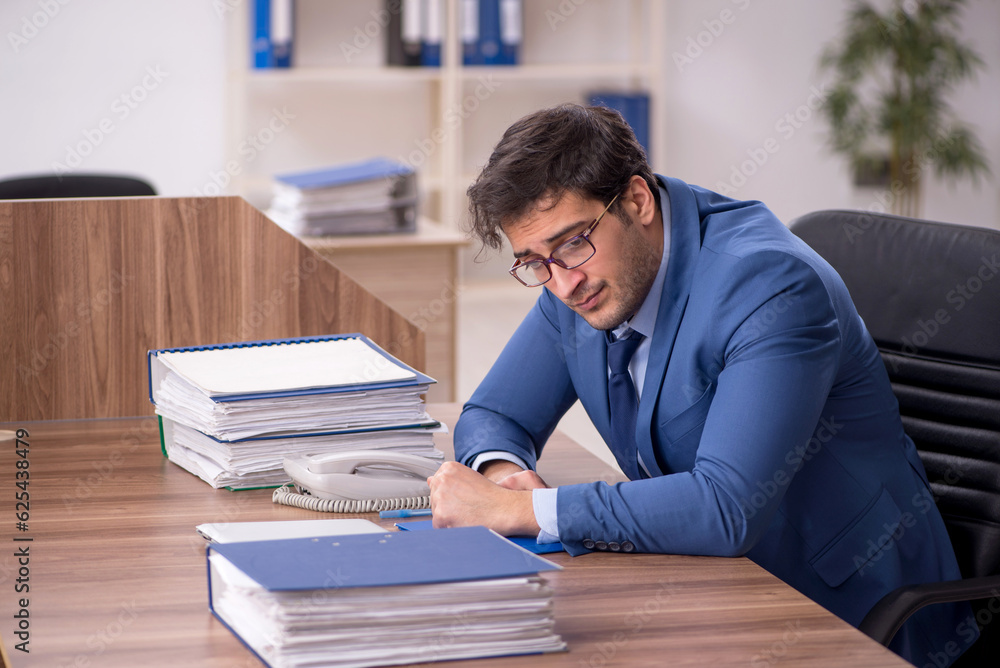 Young male employee and too much work in the office Young male employee and too much work in the office