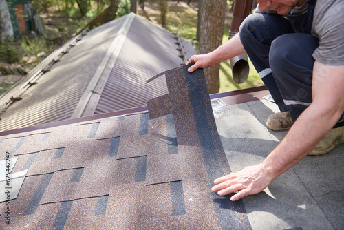A close-up of the master's hands on the roof mounts flexible tiles.