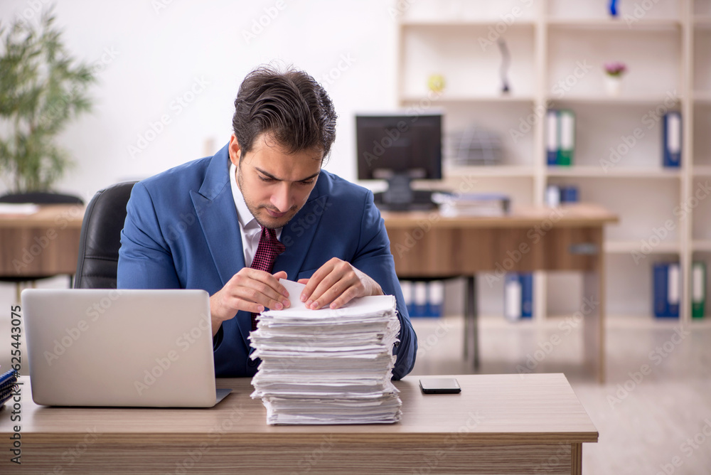 Young male employee and too much work in the office Young male employee and too much work in the office
