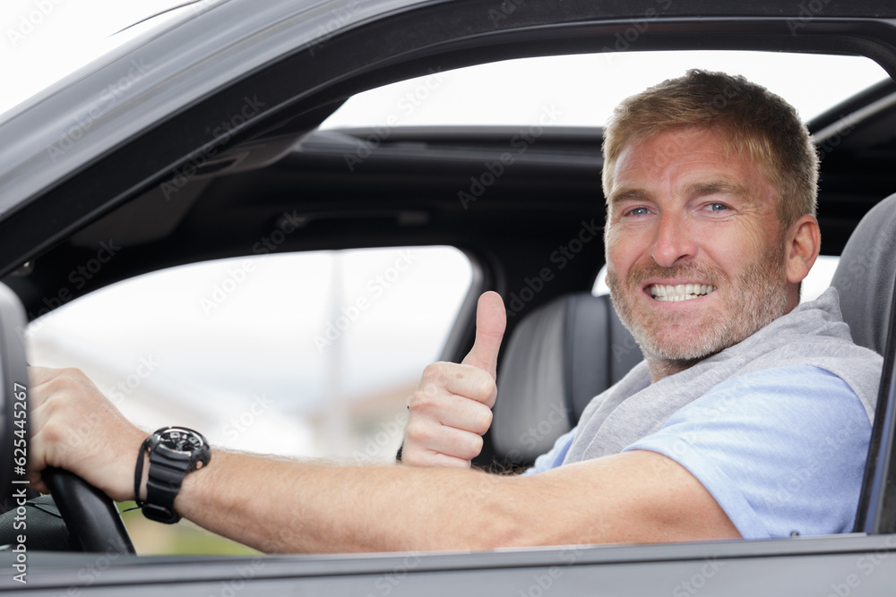 middle-aged male driver holding thumbs up through car window