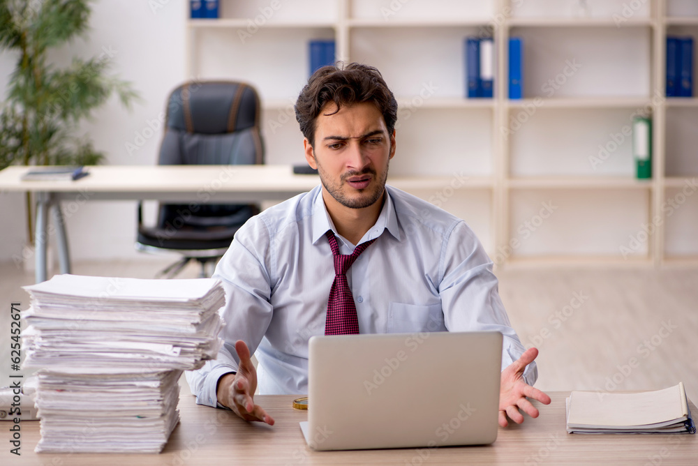 Young male employee and too much work in the office Young male employee and too much work in the office