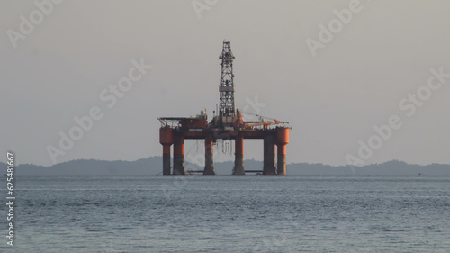 Offshore oil platform drilling site or oil rig project seen far in the middle of the sea. photo