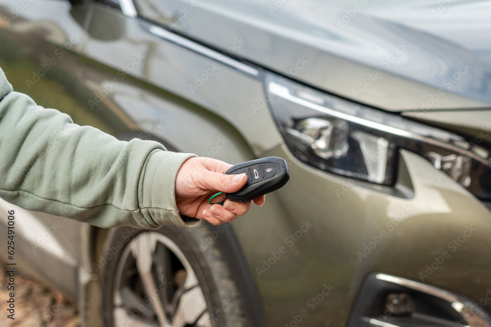 Person with a car key in the hand stands front car. Insurance, loan and buying car concept Person with a car key in the hand stands front car. Insurance, loan and buying car concept