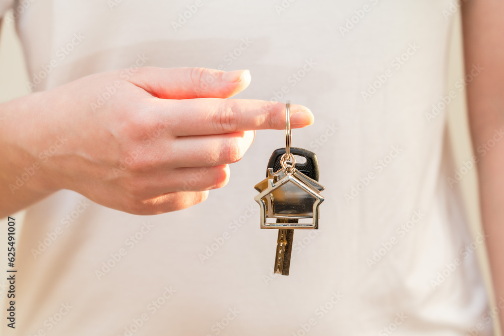 Obraz premium Woman holding key with keychain in the shape of the house