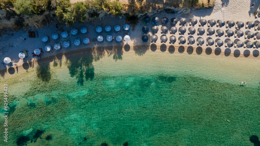 Aerial view of sandy beach with tourists swimming in beautiful clear sea water. Aerial view of amazing beach with umbrellas and turquoise sea at sunset. Mediterranean sea