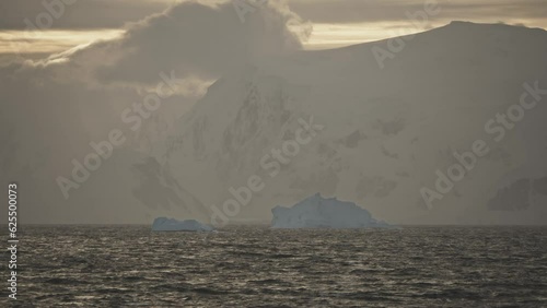 Evening or morning golden sun shining on coastline in Antarctica with snow and ice photo