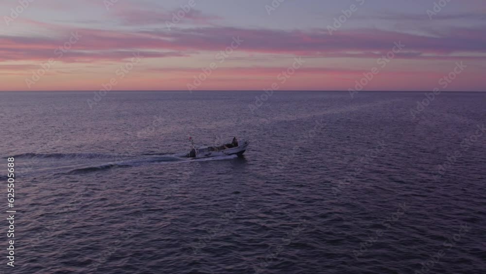 Small boat is cruising on atlantic ocean near Albufeira at sunrise, aerial Small boat is cruising on atlantic ocean near Albufeira at sunrise, aerial