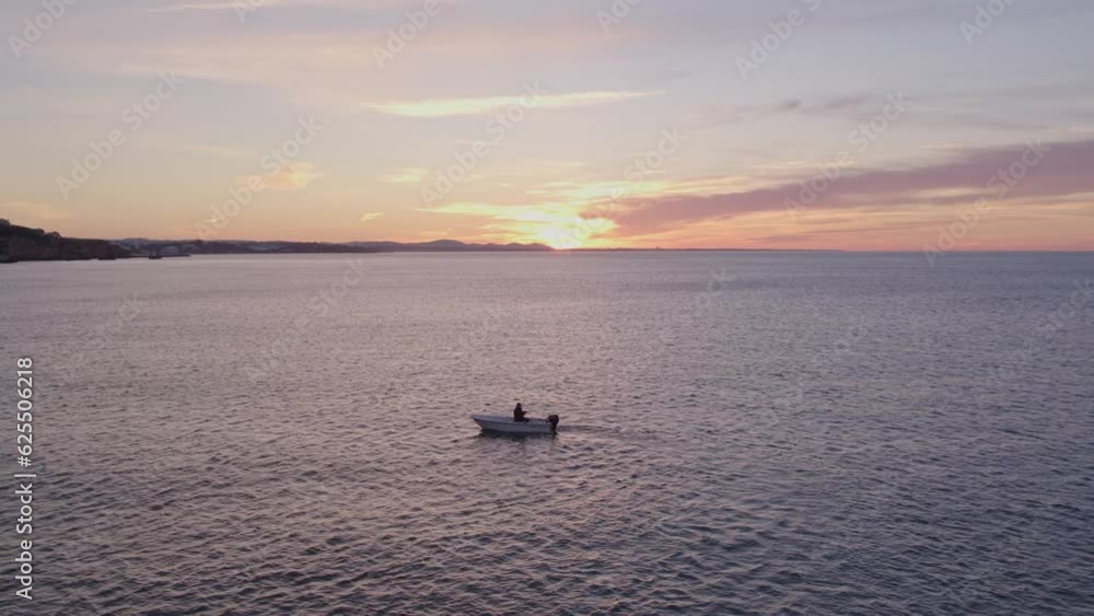 Man is fishing in small boat on calm sea during sunrise, aerial Man is fishing in small boat on calm sea during sunrise, aerial