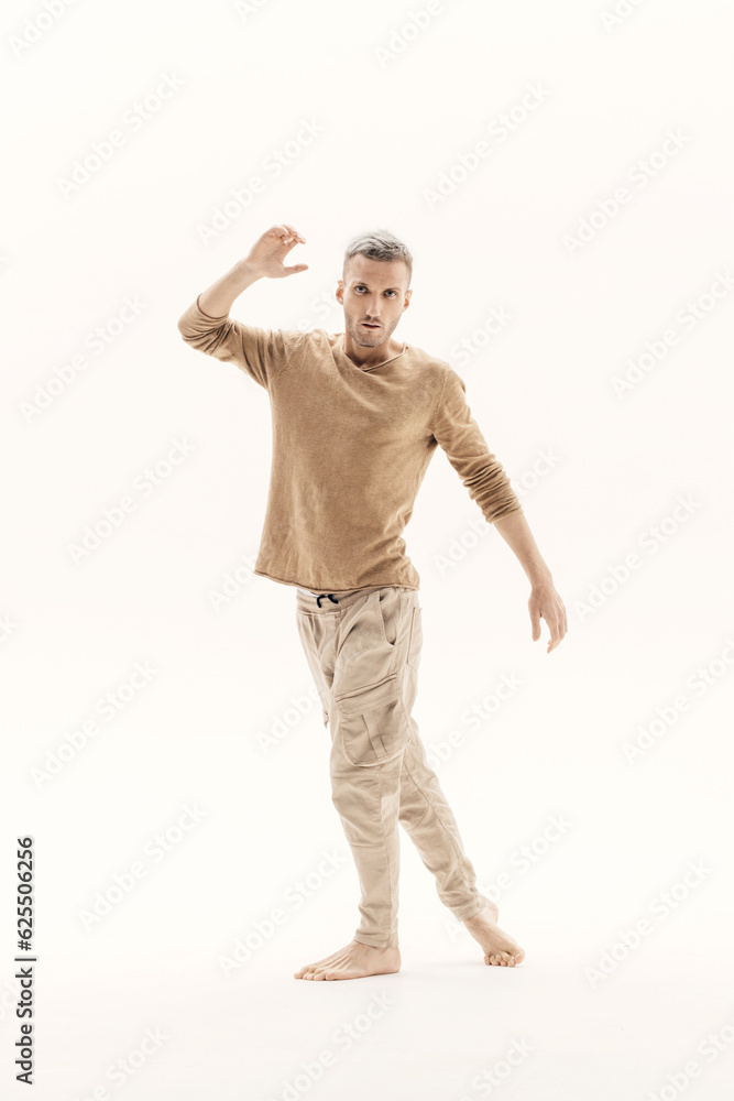 A young man in a beige jumper and cargo pants on a white background. A young man in a beige jumper and cargo pants on a white background.