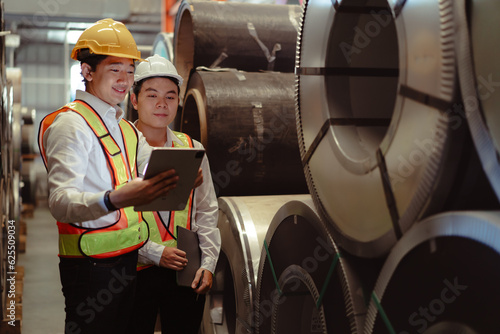 Skilled manager train young technician to work in metalwork production factory. Asian industrial engineer standing at manufacturing facility do machine technology job training in heavy metal industry