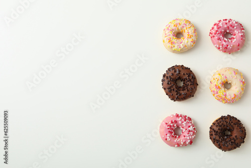 Chocolate, white and pink donuts on white background, space for text