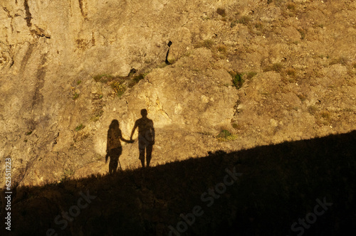 Silhouette of a couple in love on a rock, shadow from the echo at night, holding hands