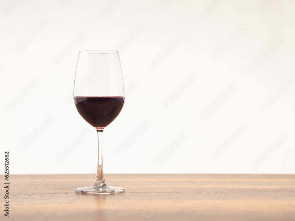 A glass of red wine on the table against a gray background.