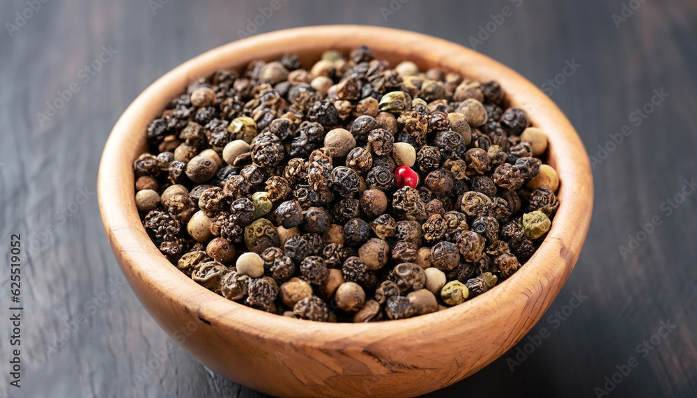 Peppercorns in a wooden bowl on a dark background Peppercorns in a wooden bowl on a dark background
