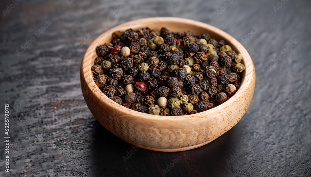 Peppercorns in a wooden bowl on a dark background Peppercorns in a wooden bowl on a dark background