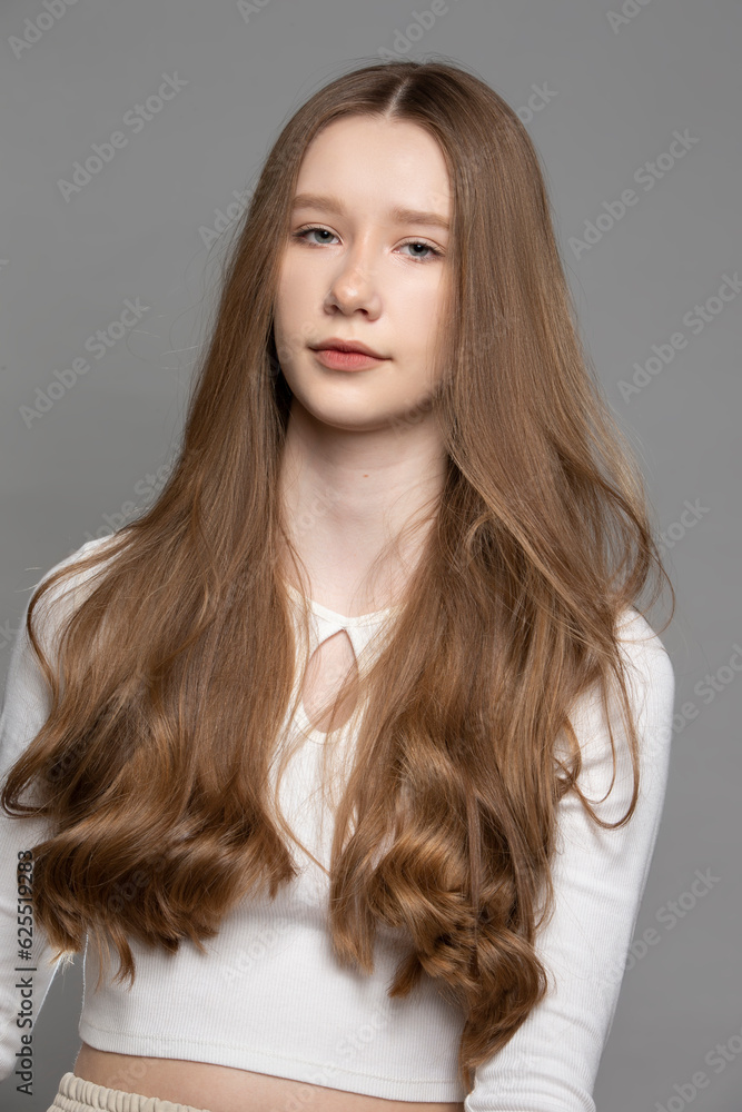 Teenage girl with blond long hair on a gray background. Teenage girl with blond long hair on a gray background.