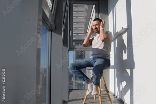 man wearing headphones relaxed on the balcony of your apartment. concept without stress. mental health. work from vacation home