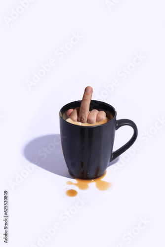 Big black espresso cup with a middle finger sticking out of it on a white background with coffee stains.