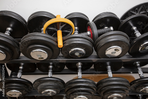 Black dumbbells of different weights in the gym.