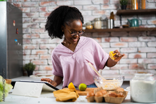 Young African woman in kitchen. Beautiful woman having fun while making dough © JustLife