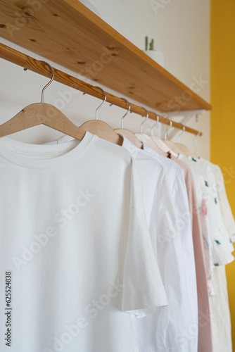 White t-shirt hanging on a wooden hanger in the interior