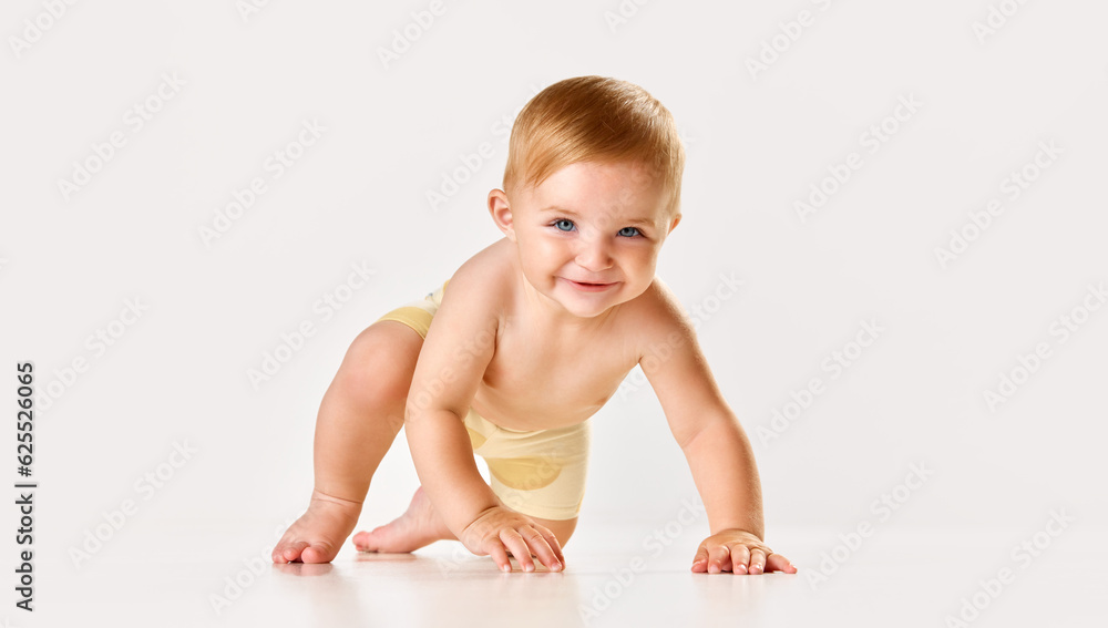 Beautiful, cute baby, girl, toddler smiling, playing and crawling on floor against white studio background. Concept of childhood, newborn lifestyle, happiness, care. Copy space for ad Beautiful, cute baby, girl, toddler smiling, playing and crawling on floor against white studio background. Concept of childhood, newborn lifestyle, happiness, care. Copy space for ad